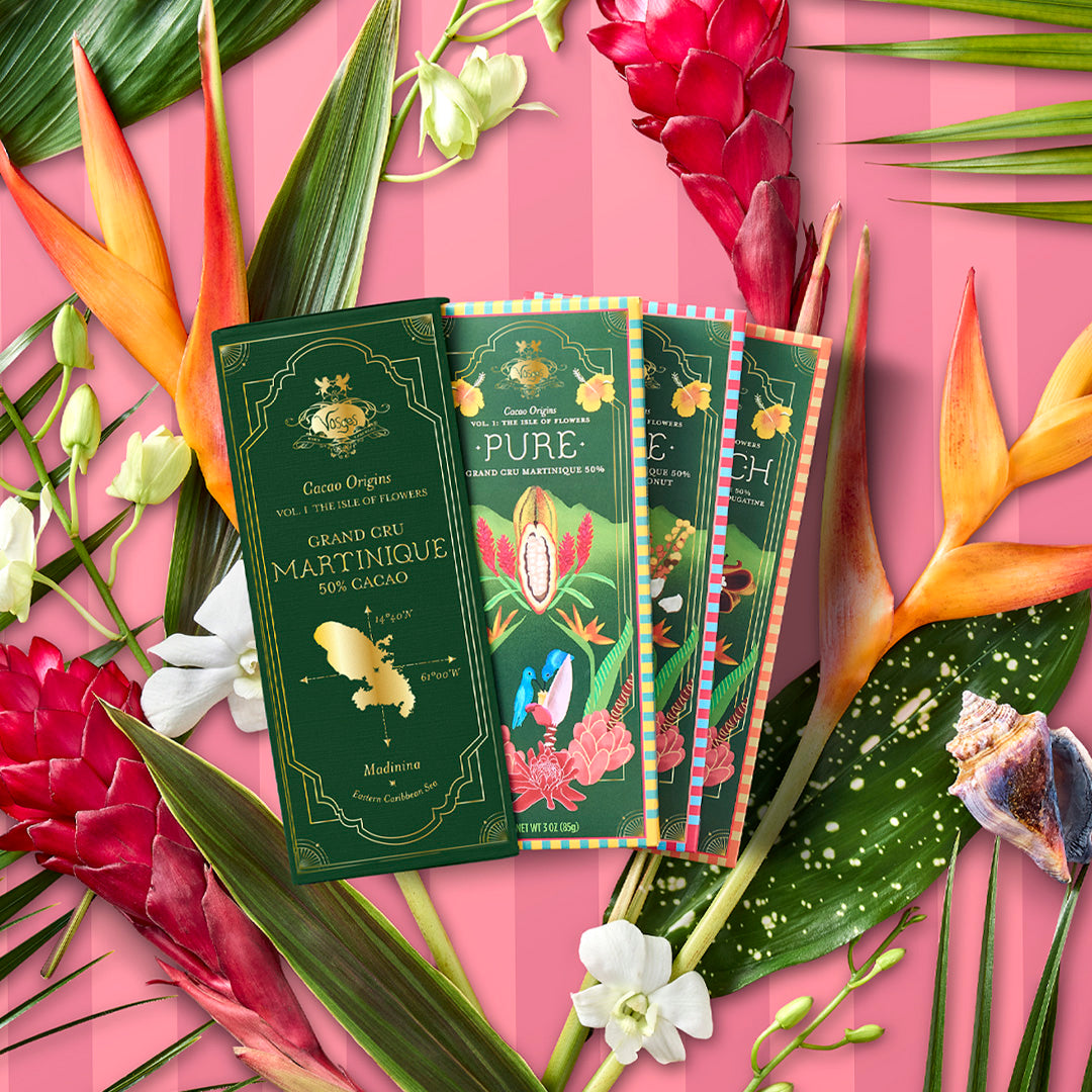 Three green chocolate packaging on a pink background with tropical flowers and leaves.