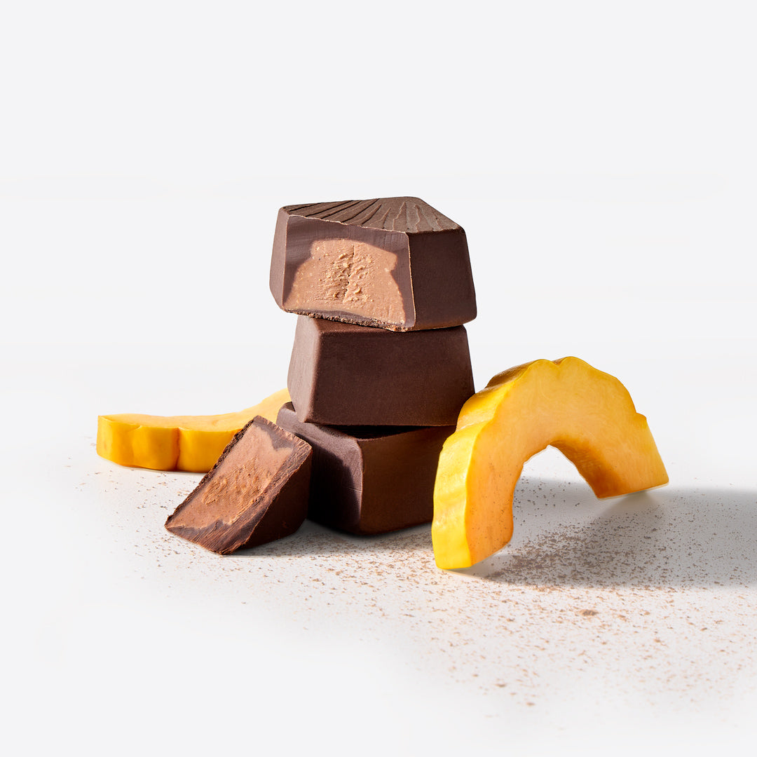 Three dark chocolate bonbons stacked with peanut butter centers beside mango slices