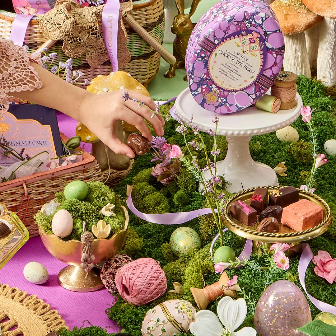 Easter-themed display with chocolate eggs, flowers, and decorative items on a green surface.