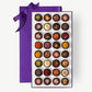 Assorted chocolates in a purple box with a bow on a white background