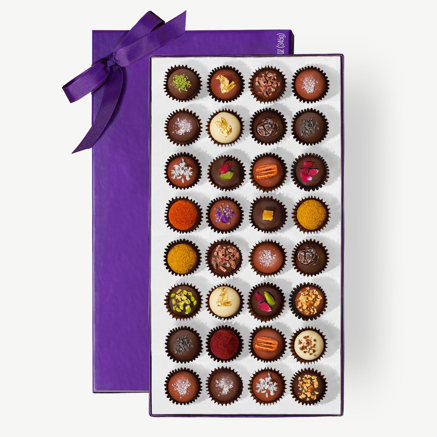 Assorted chocolates in a purple box with a bow on a white background