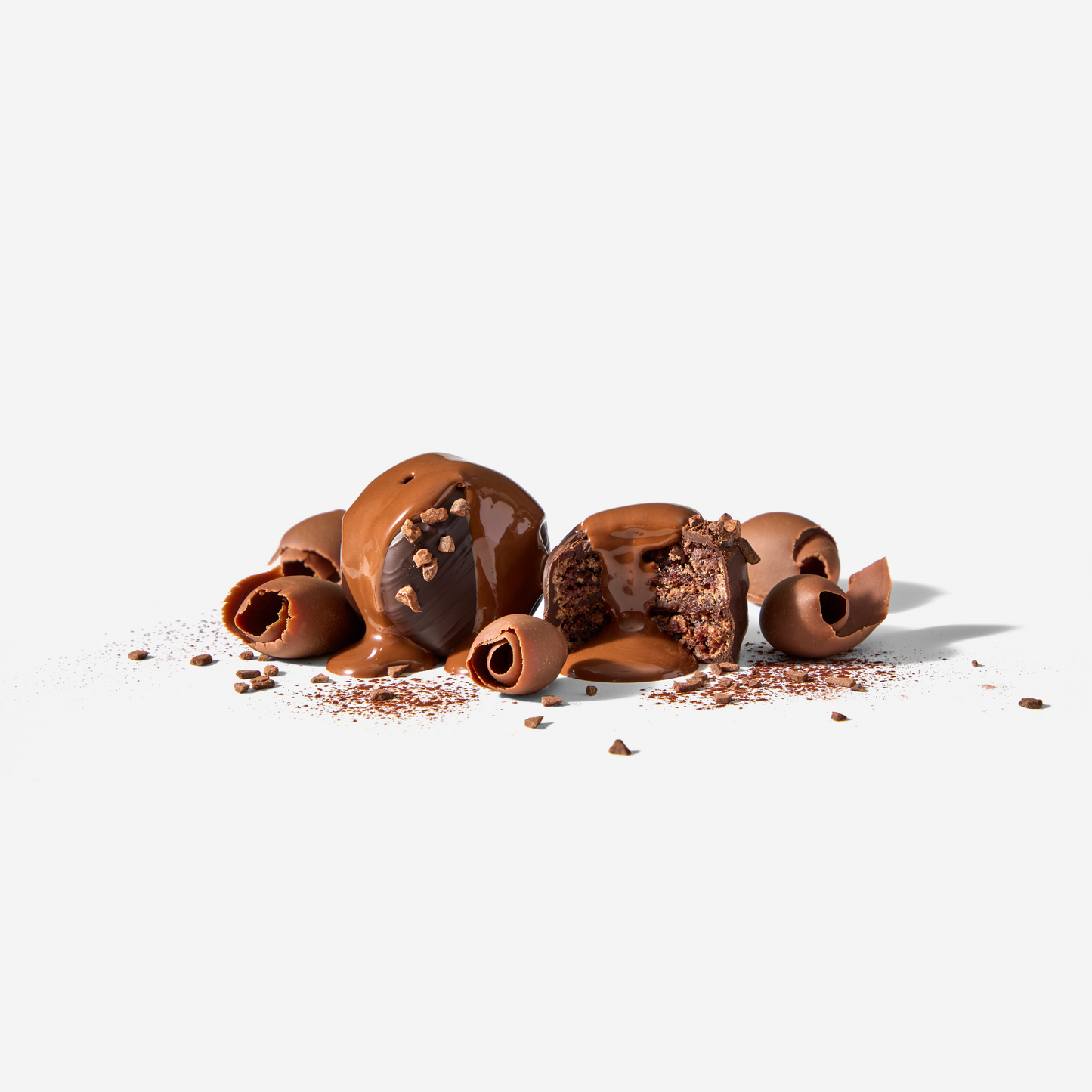 Chocolate truffles with a few broken open on a white background