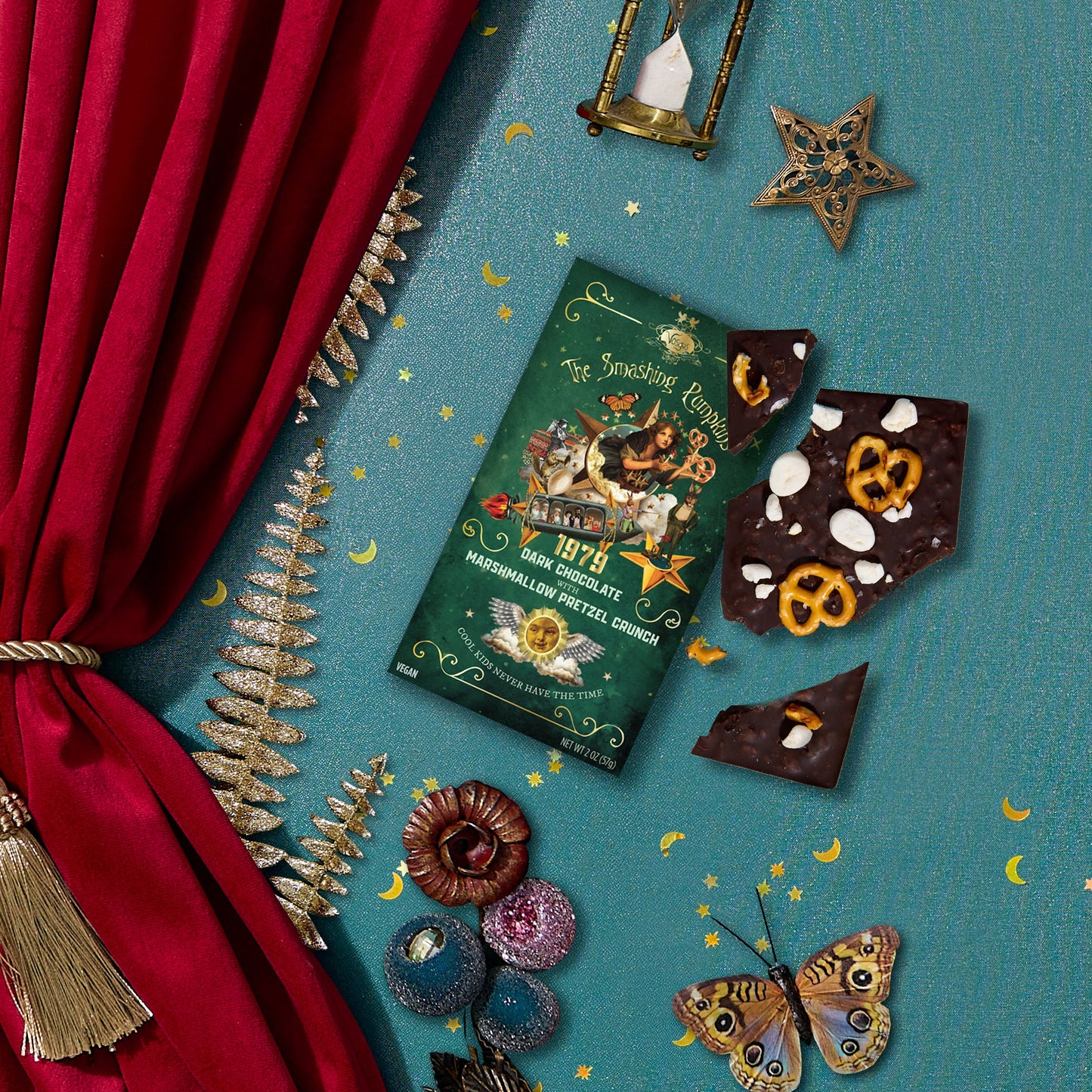 Chocolate bars with decorative packaging on a blue surface with red curtain and decorative elements.