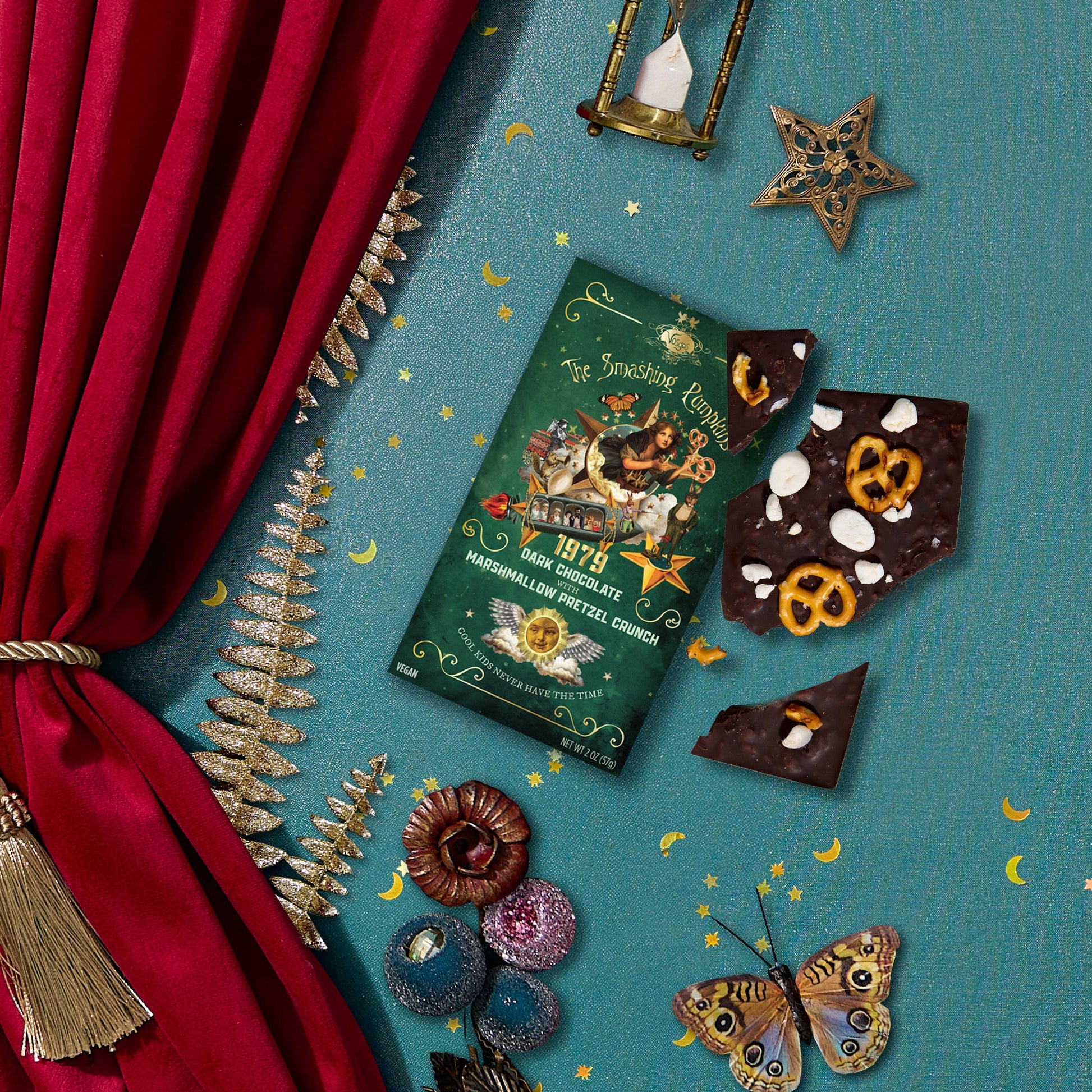 Chocolate bars with decorative packaging on a blue surface with red curtain and decorative elements.