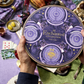 Hand holding Enchanted Magic Chocolate Tower tin featuring celestial purple artwork