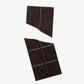 Vosges Mo's Dark Chocolate Bacon Bar broken in two on a light grey background.