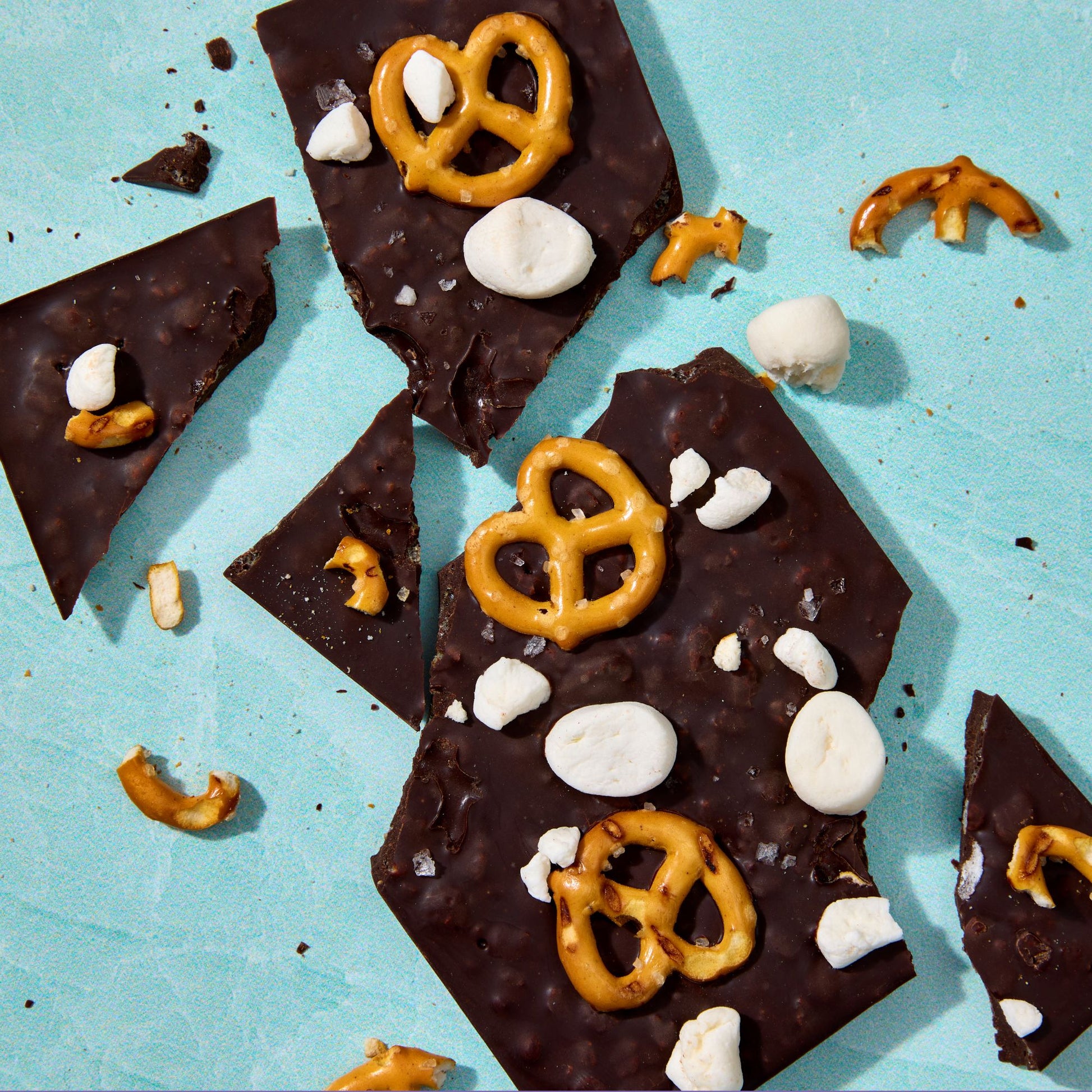 Chocolate bark with pretzels and marshmallows on a light blue background