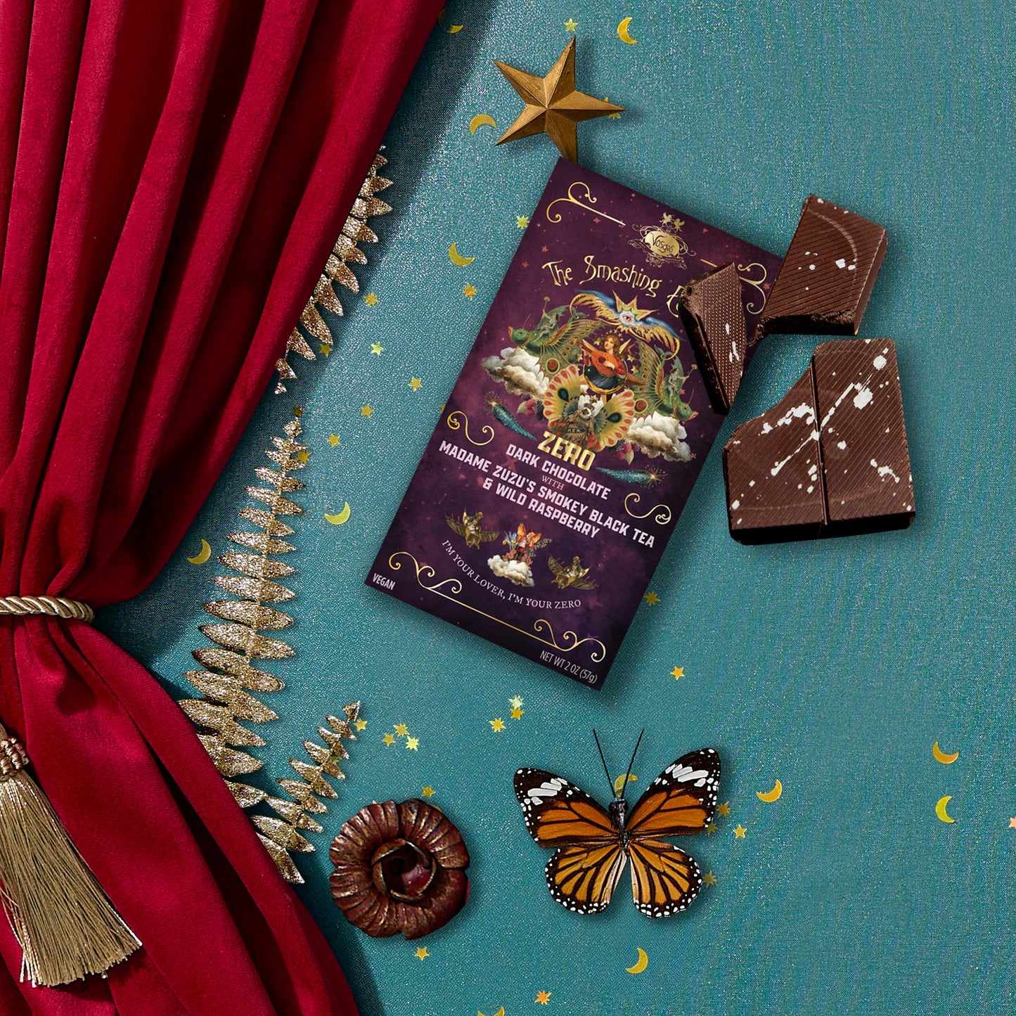 Chocolate bar with decorative packaging on a blue surface with red curtain and butterfly